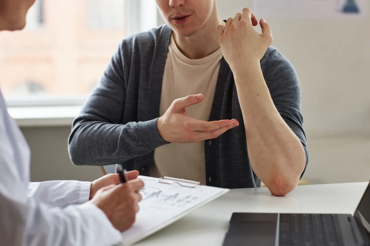 Patient discussing eczema symptoms on the elbow with a doctor during a skin consultation